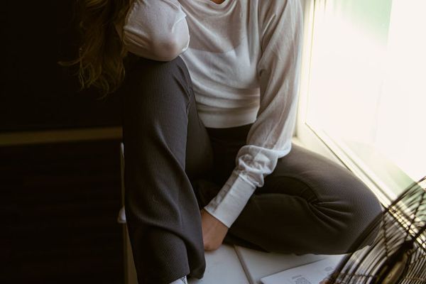 A calm person sitting by a large window, looking thoughtfully into the distance.